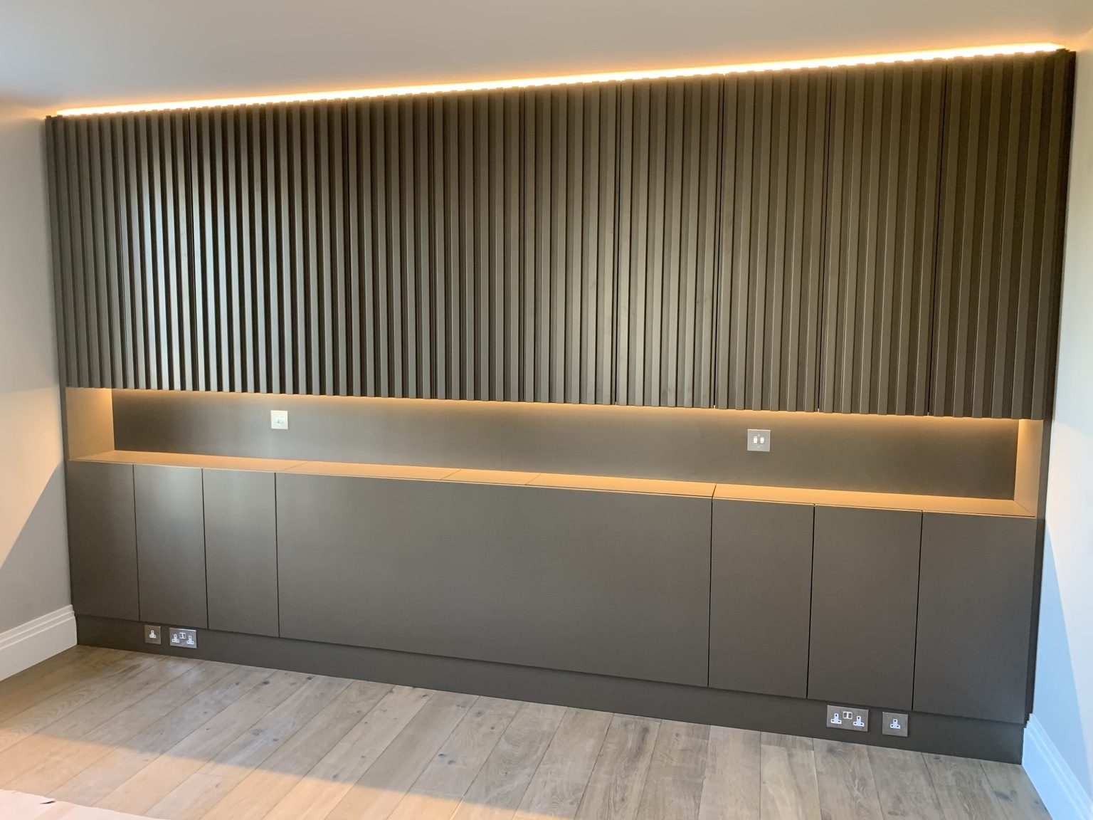 Dark bespoke fitted cabinetry with integrated lighting